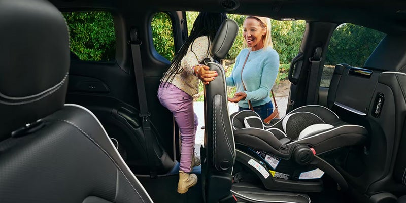 Interior view of a minivan with a child safety seat installed, showing easy access through the rear seating area as occupants enter the vehicle