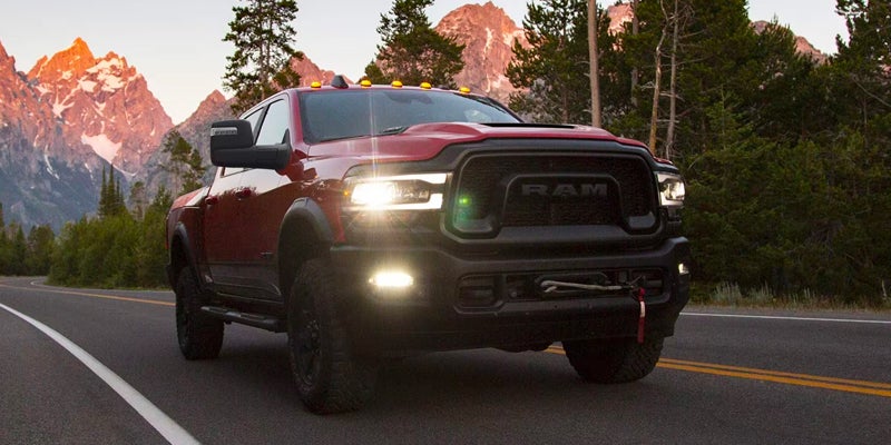 Red Ram truck with bright headlights on a mountain road at dusk