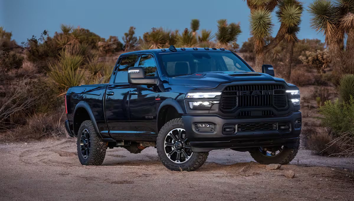 Dark blue Ram Power Wagon truck on a dirt road in a desert landscape with Joshua trees