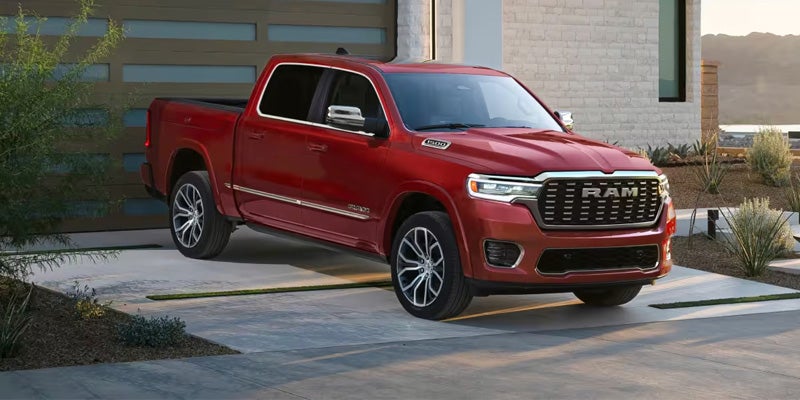 Red full-size pickup truck parked in the driveway of a modern home, shown from a front three-quarter angle